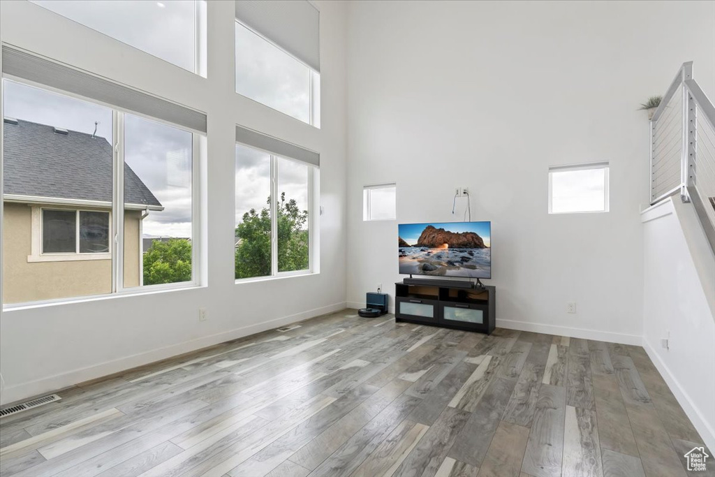 Living room featuring wood finished floors, plenty of natural light, baseboards, and a high ceiling