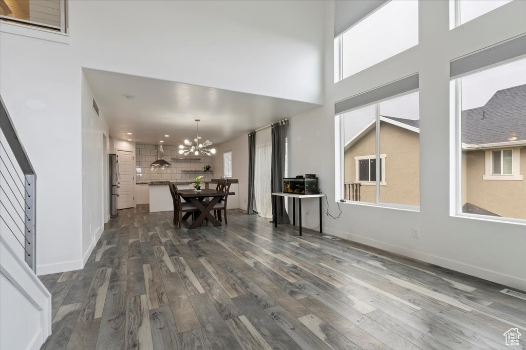 Dining space with dark wood-type flooring, a chandelier, a towering ceiling, and baseboards