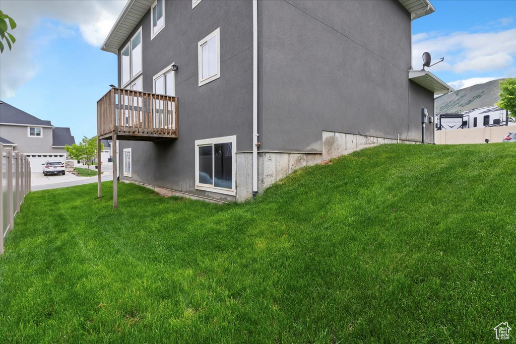 Back of property with a yard, stucco siding, and a wooden deck