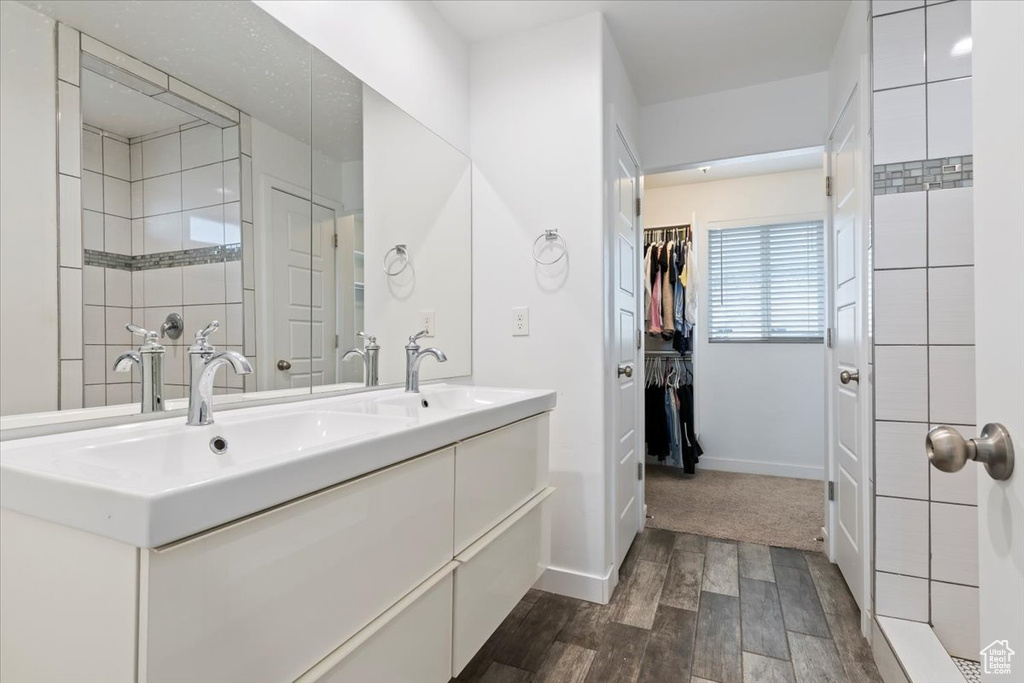 Full bathroom with wood finished floors, double vanity, baseboards, and a walk in closet