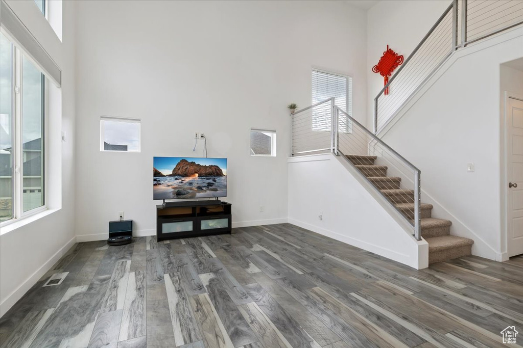 Living room with a towering ceiling, stairway, wood finished floors, and healthy amount of natural light