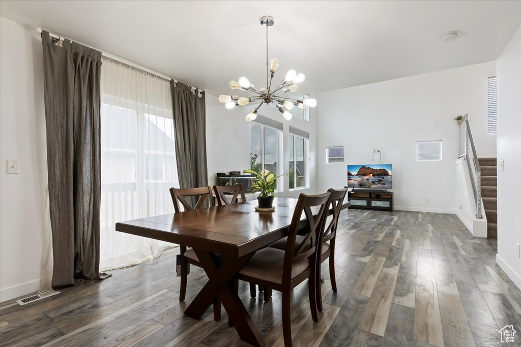 Dining area with a chandelier, wood finished floors, stairs, and baseboards