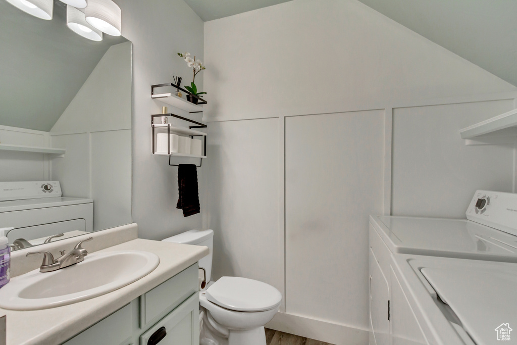 Bathroom with washer / clothes dryer, lofted ceiling, toilet, and vanity