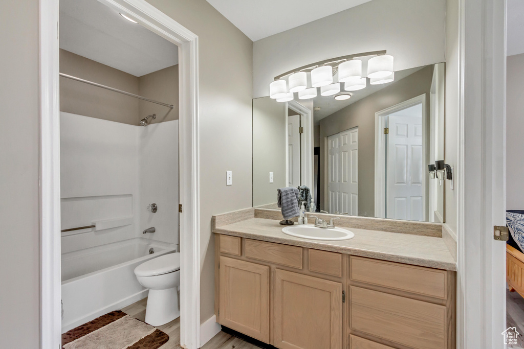 Bathroom featuring vanity, toilet, shower / bath combination, and wood finished floors