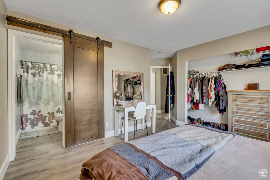 Bedroom featuring a closet, a barn door, wood finished floors, and baseboards