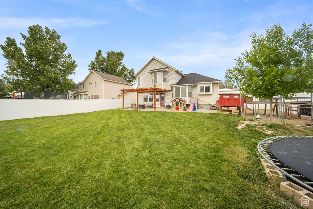 Back of house with a trampoline, a pergola, and a patio