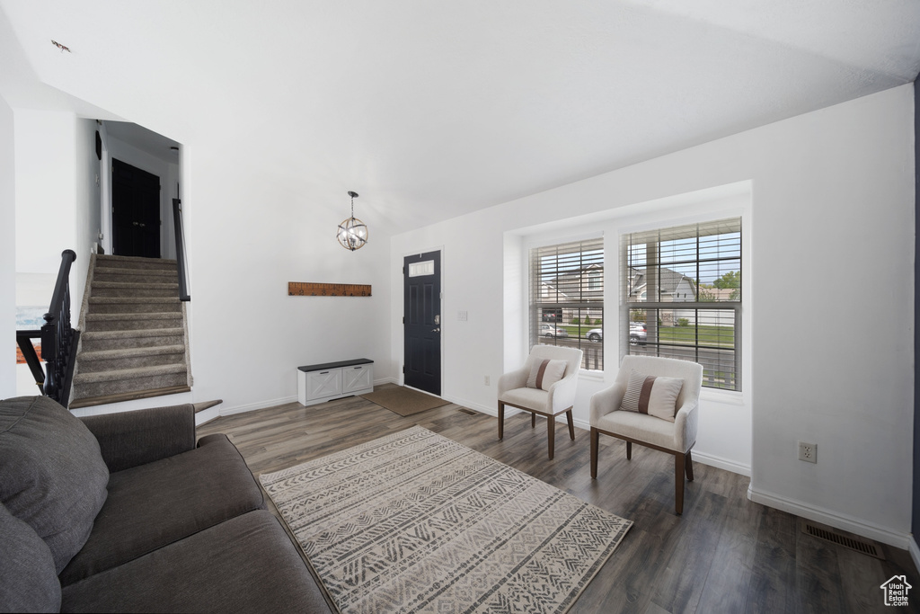 Living room with vaulted ceiling, dark wood-style floors, baseboards, and a chandelier