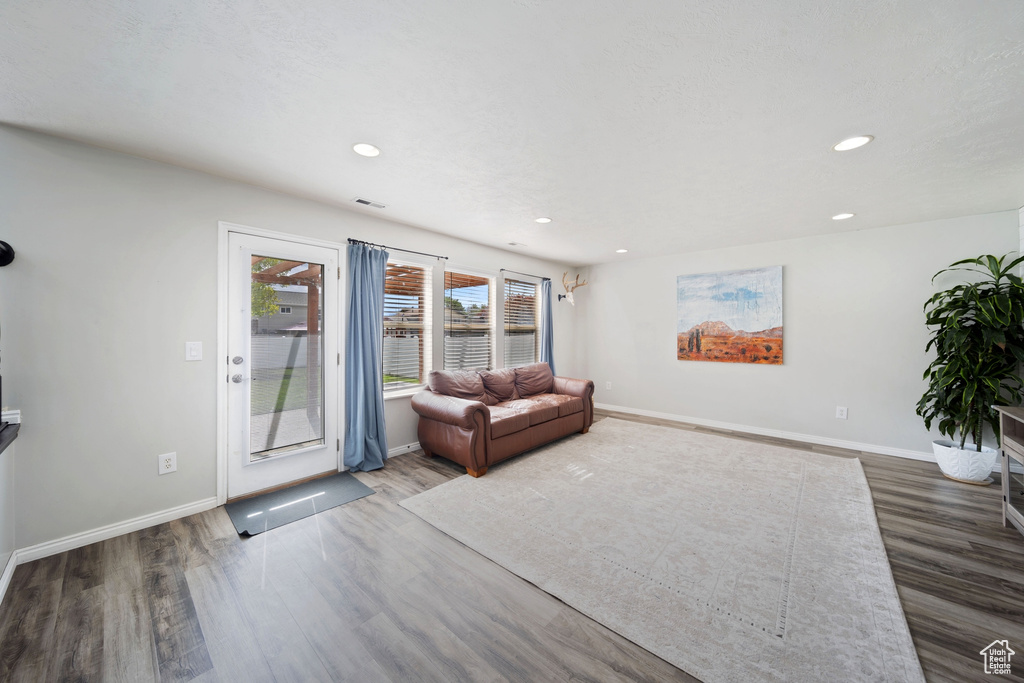 Living area with wood finished floors, baseboards, and recessed lighting