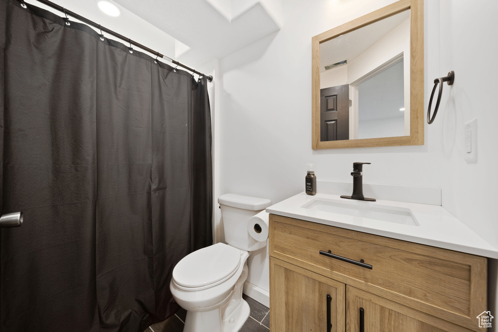 Bathroom featuring toilet, vanity, curtained shower, and baseboards