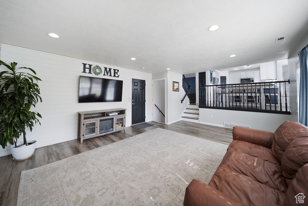 Living room featuring wood finished floors, baseboards, recessed lighting, and stairs
