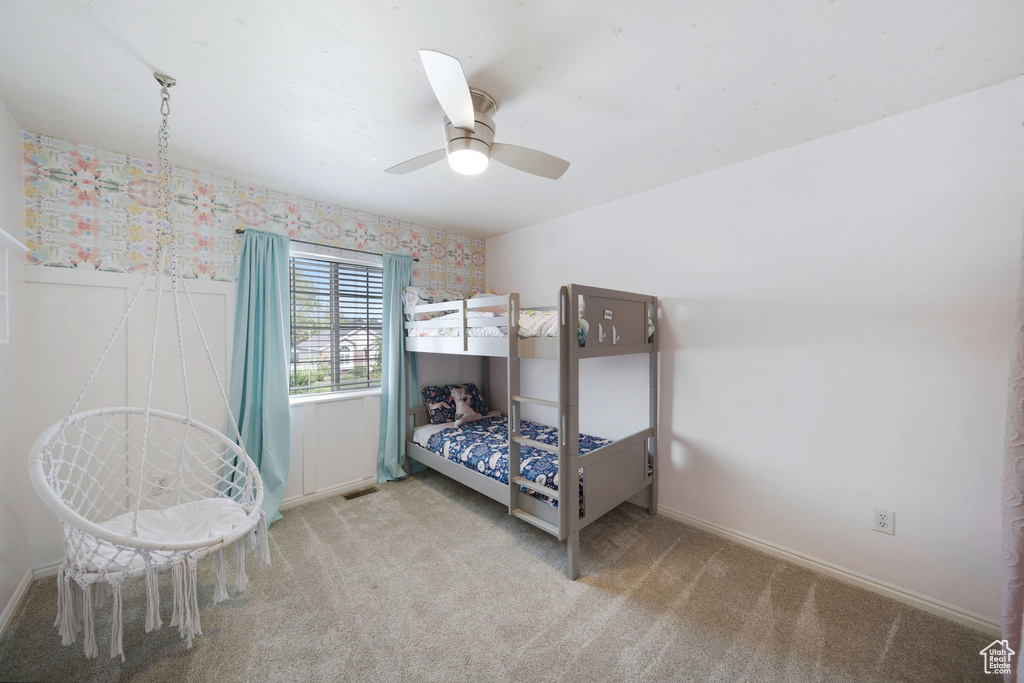 Carpeted bedroom featuring baseboards, wallpapered walls, and a ceiling fan