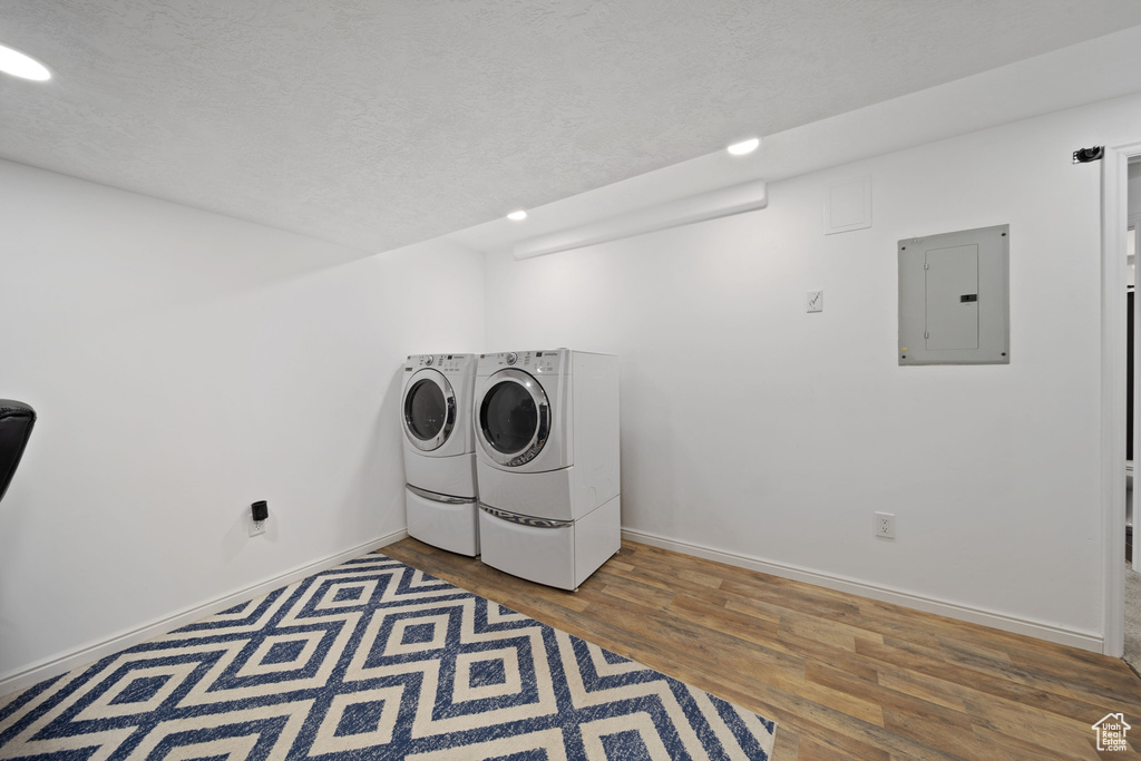 Laundry area featuring electric panel, separate washer and dryer, baseboards, wood finished floors, and recessed lighting