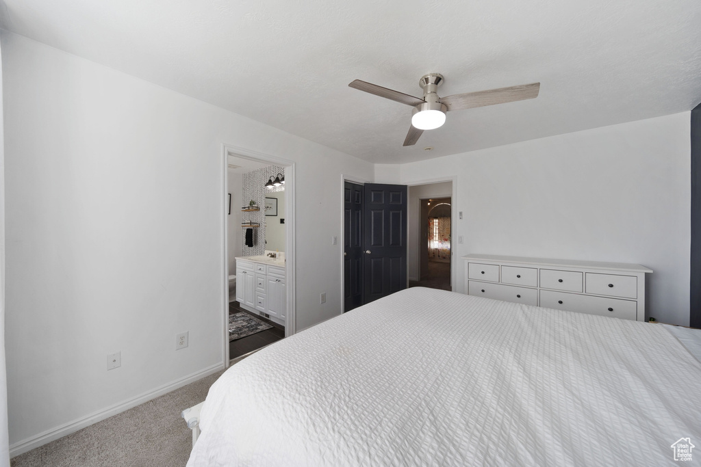 Carpeted bedroom featuring baseboards, connected bathroom, and ceiling fan