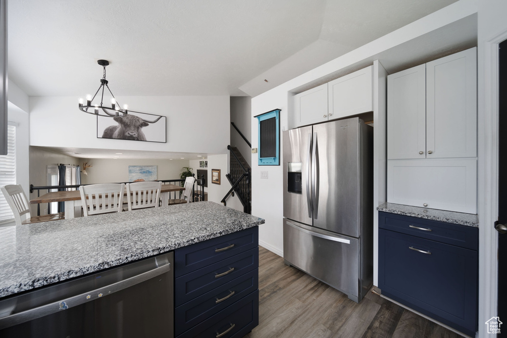 Kitchen with stainless steel fridge, dishwashing machine, a chandelier, white cabinetry, and dark wood-type flooring