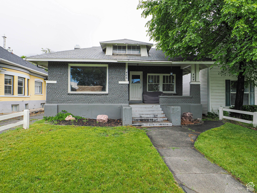 Bungalow-style house featuring brick siding, covered porch, and roof with shingles