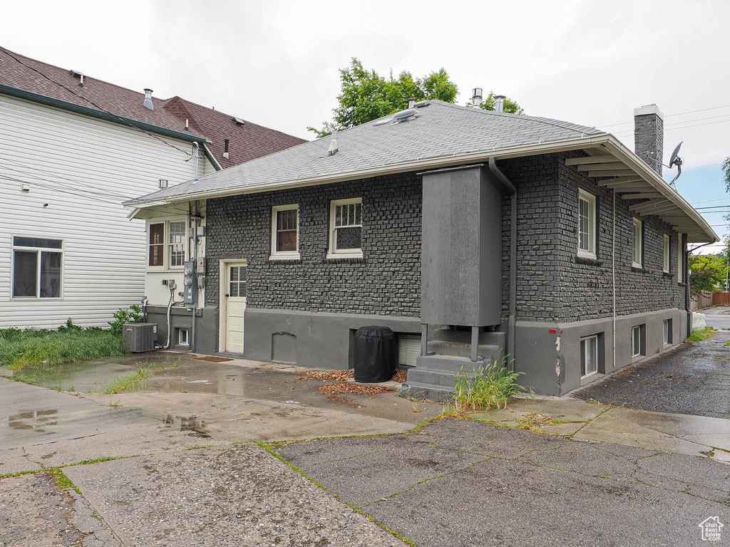 View of property exterior featuring central air condition unit and a chimney