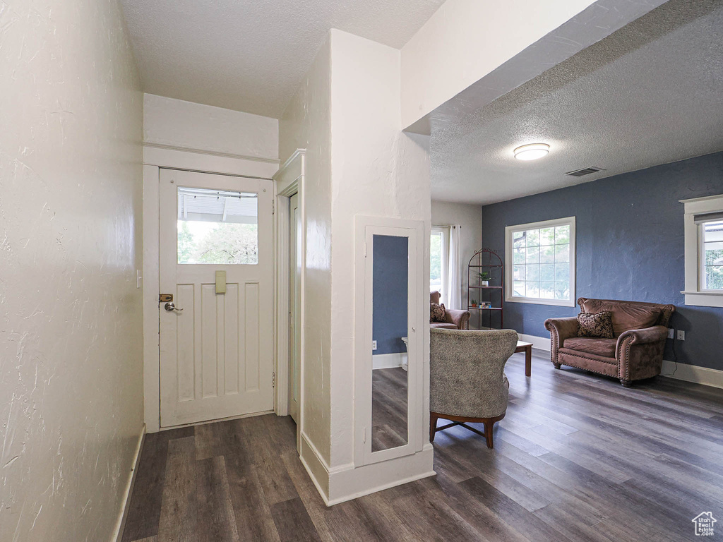 Foyer with dark wood finished floors, a textured ceiling, baseboards, and a textured wall
