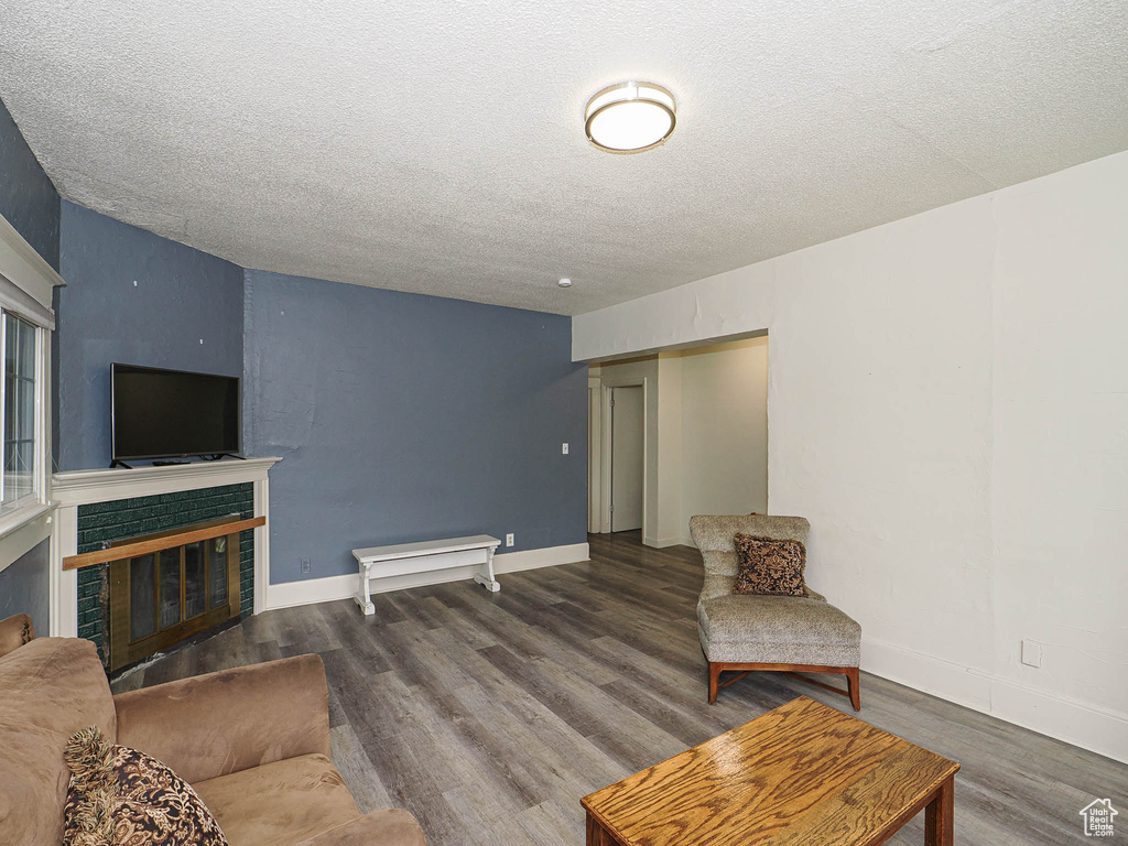 Living area with wood finished floors, a textured ceiling, a fireplace, and baseboards