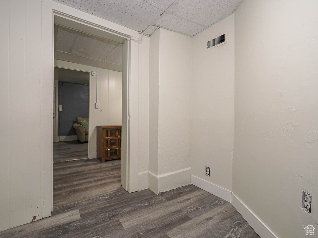 Spare room with dark wood finished floors, a paneled ceiling, and baseboards