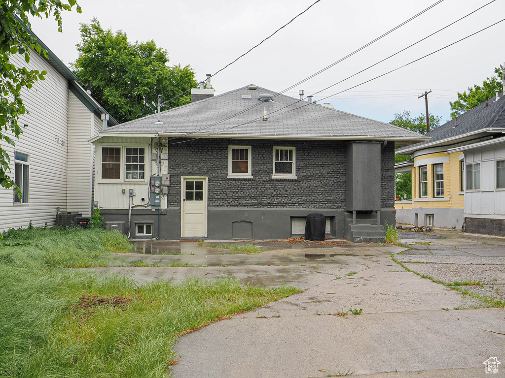 Rear view of property featuring a shingled roof, entry steps, and central AC
