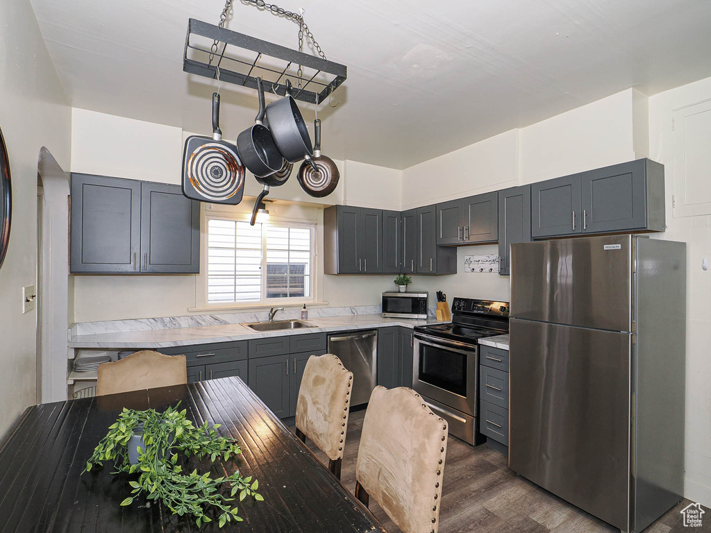 Kitchen featuring stainless steel appliances, a sink, dark wood finished floors, and gray cabinetry