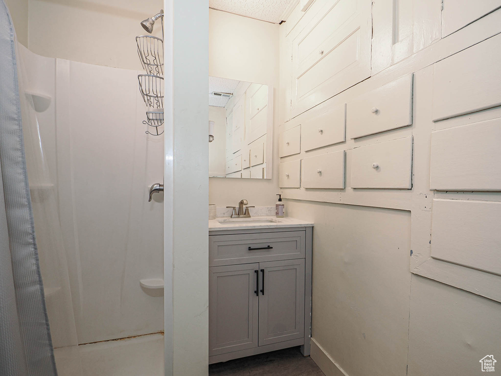 Bathroom with a stall shower, vanity, and baseboards