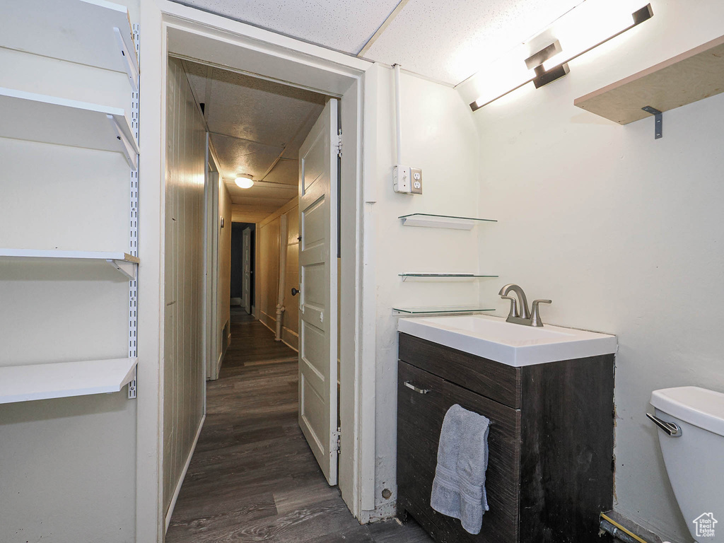 Half bath featuring toilet, wood finished floors, and vanity