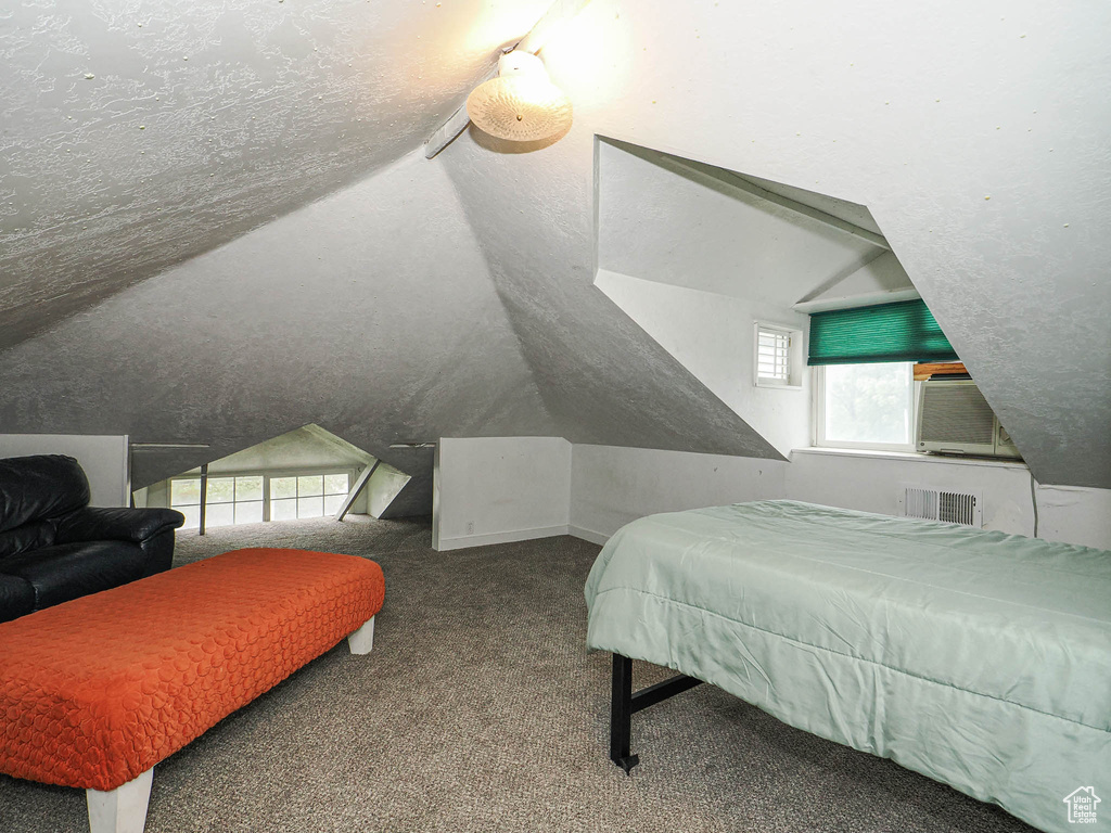 Carpeted bedroom with lofted ceiling and cooling unit