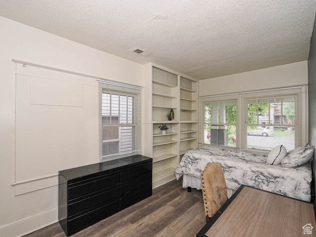 Bedroom with dark wood-type flooring, a textured ceiling, and baseboards