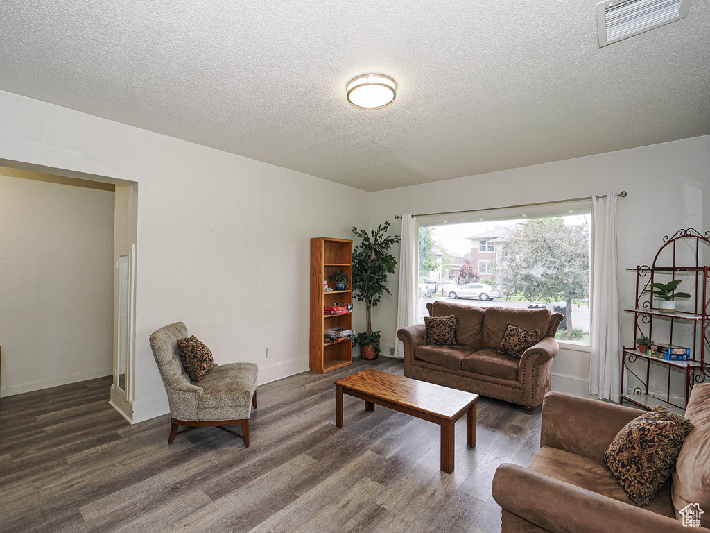 Living area with wood finished floors, a textured ceiling, and baseboards