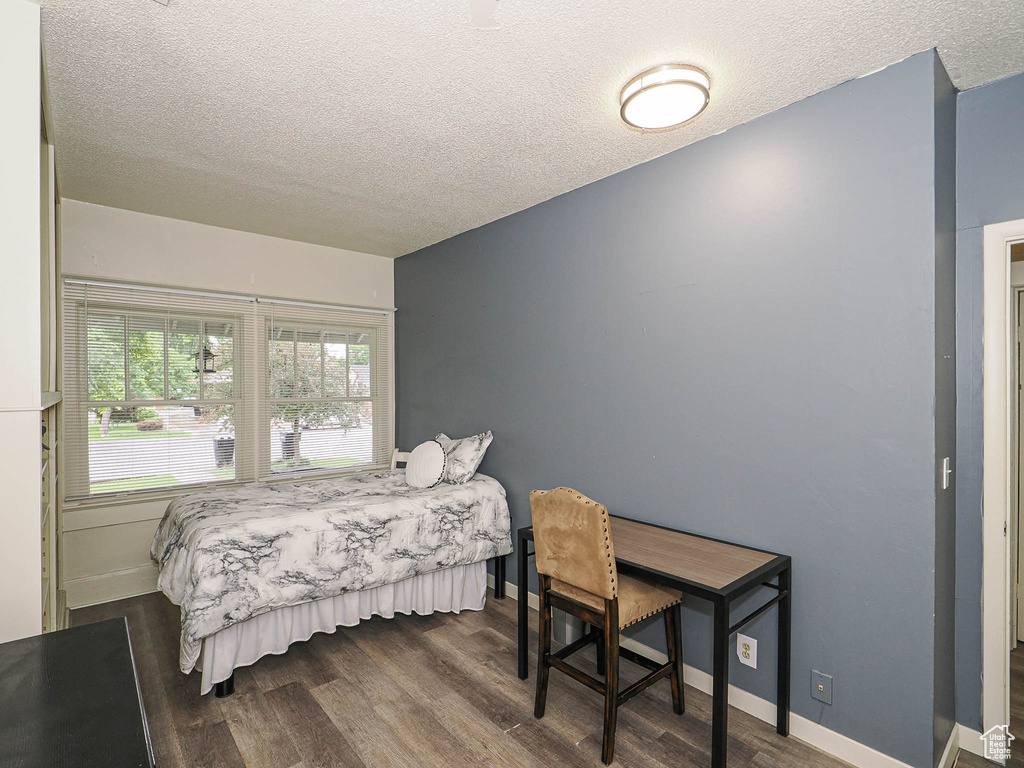 Bedroom featuring a textured ceiling, wood finished floors, and baseboards