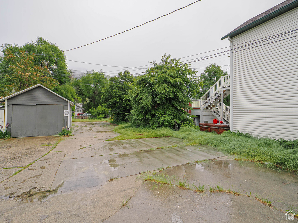 Exterior space with stairway, a garage, an outbuilding, and driveway