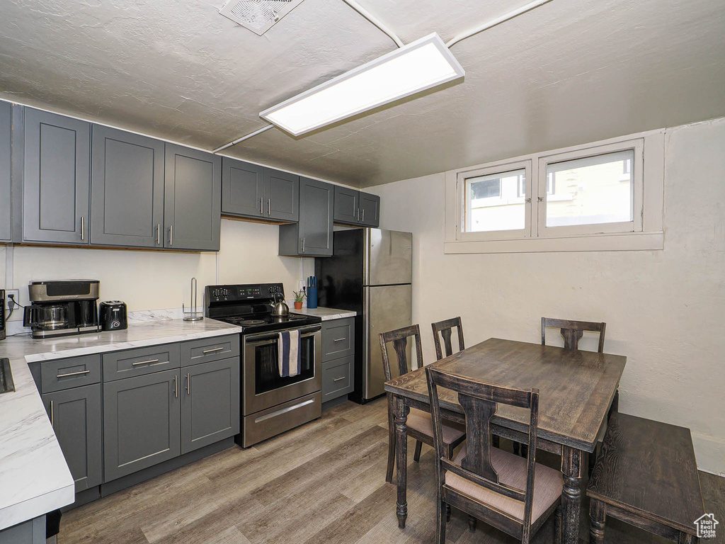 Kitchen with stainless steel appliances, light wood-style floors, and gray cabinetry