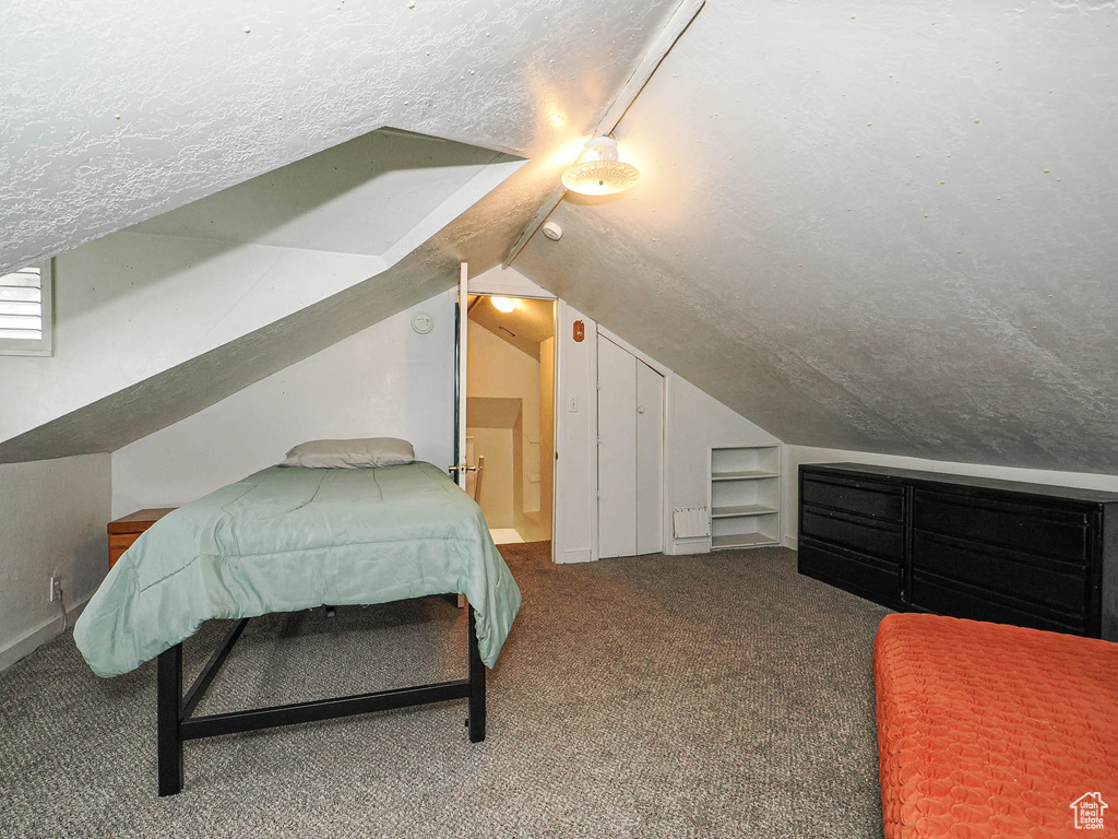 Bedroom featuring vaulted ceiling, carpet, and a textured ceiling