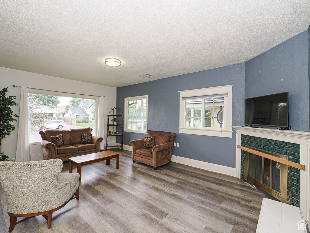 Living area featuring a textured ceiling, wood finished floors, and a fireplace