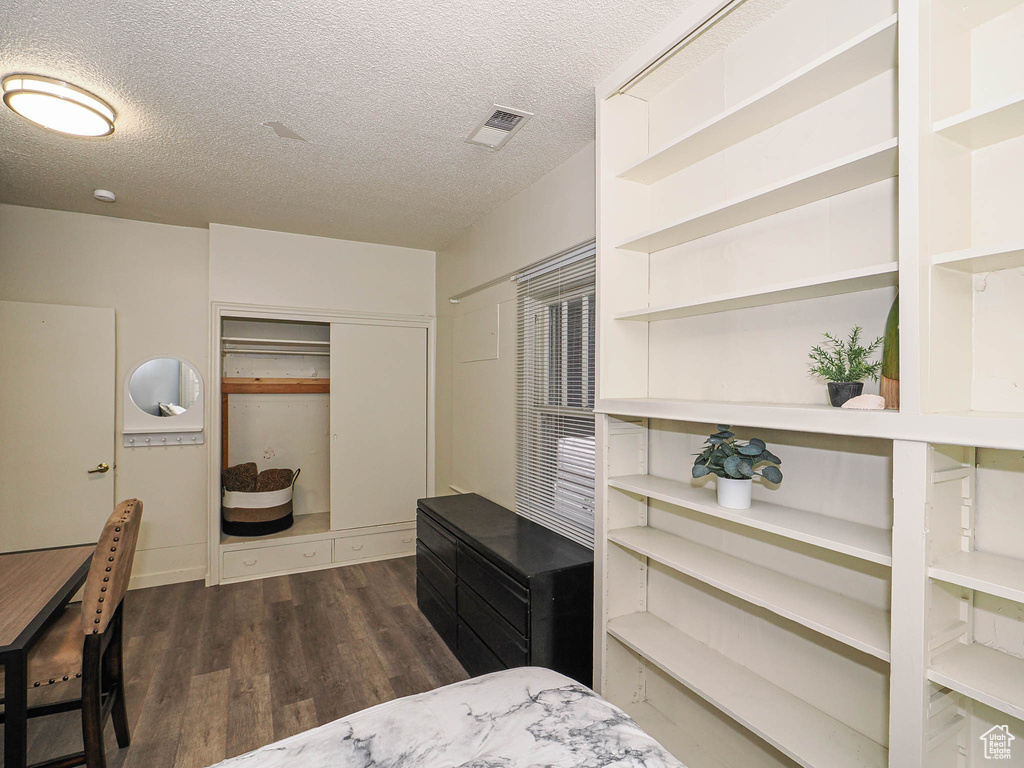 Bedroom featuring wood finished floors, a textured ceiling, and a closet