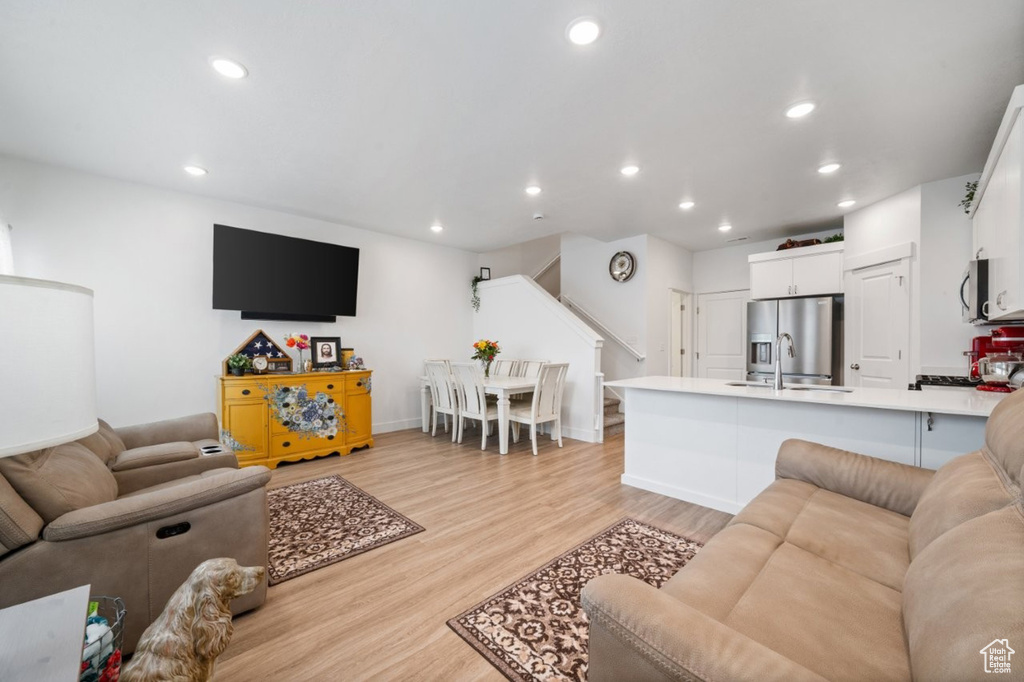 Living area with stairs, light wood finished floors, recessed lighting, and baseboards