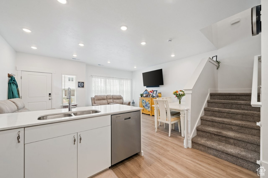 Kitchen with dishwasher, a sink, open floor plan, light wood-type flooring, and recessed lighting