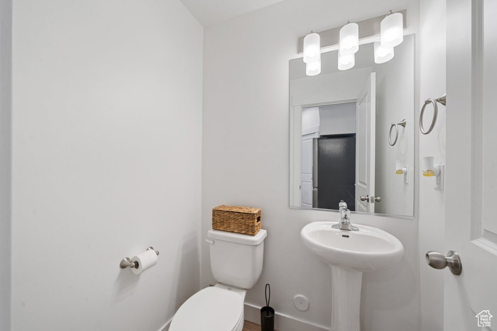Half bathroom featuring toilet, baseboards, and a sink