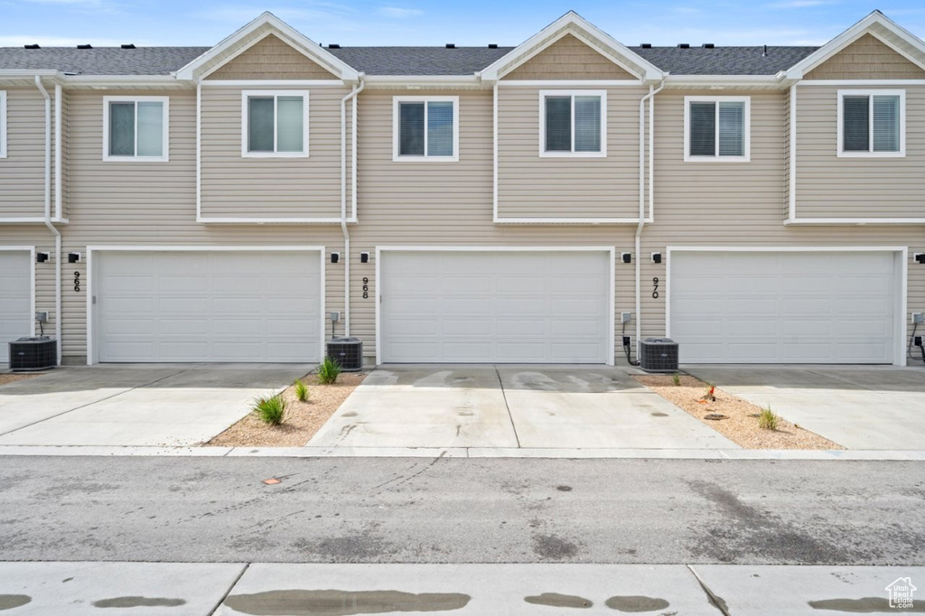 Townhome / multi-family property featuring an attached garage, driveway, and central AC