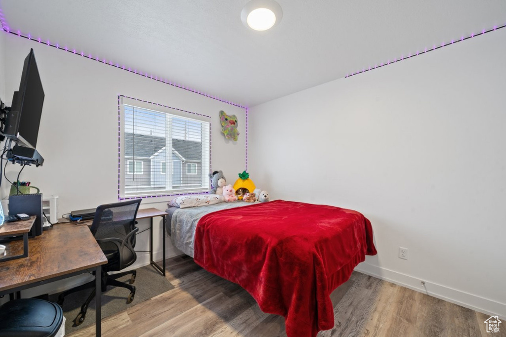 Bedroom with wood finished floors, baseboards, and an office area