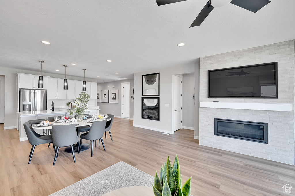 Dining area featuring a stone fireplace, baseboards, light wood-style floors, and recessed lighting