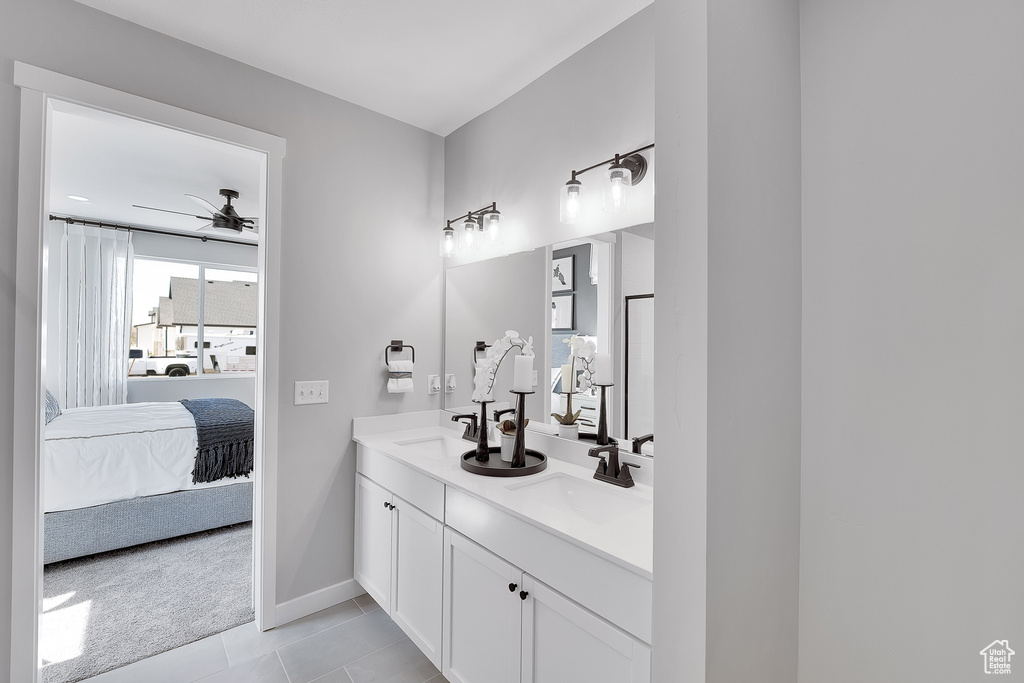 Ensuite bathroom featuring ceiling fan, baseboards, double vanity, and tile patterned flooring
