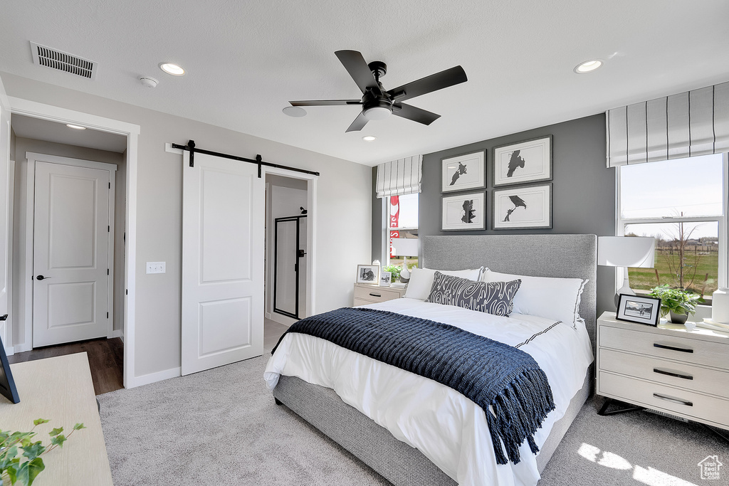 Carpeted bedroom with a barn door, recessed lighting, a ceiling fan, and baseboards