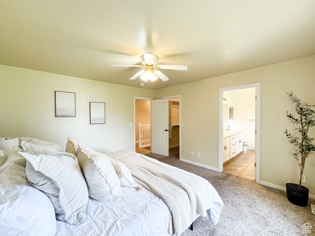 Bedroom with light colored carpet, baseboards, connected bathroom, and ceiling fan