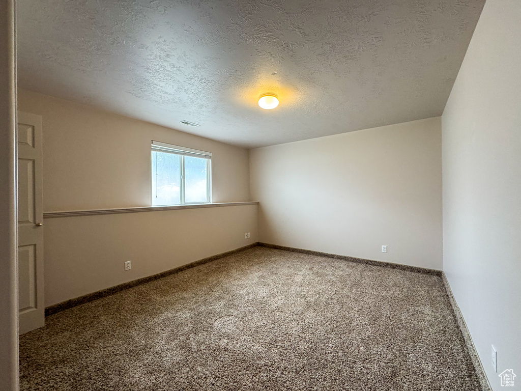 Spare room featuring carpet, a textured ceiling, and baseboards