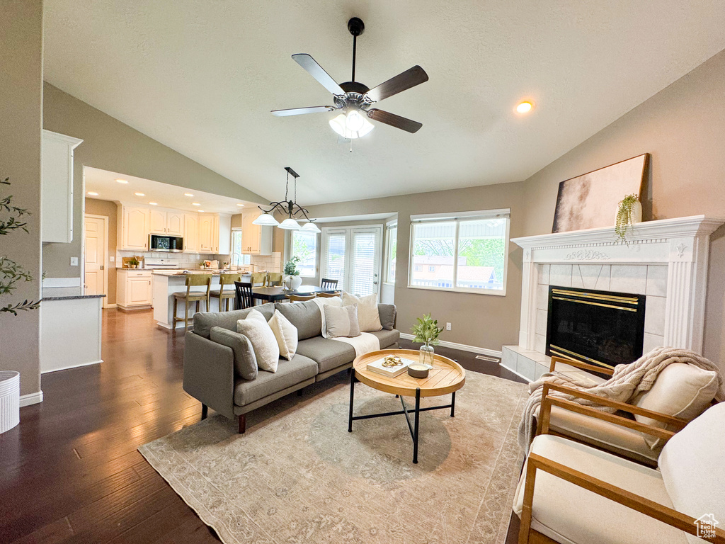 Living area featuring lofted ceiling, ceiling fan, wood finished floors, a fireplace, and baseboards