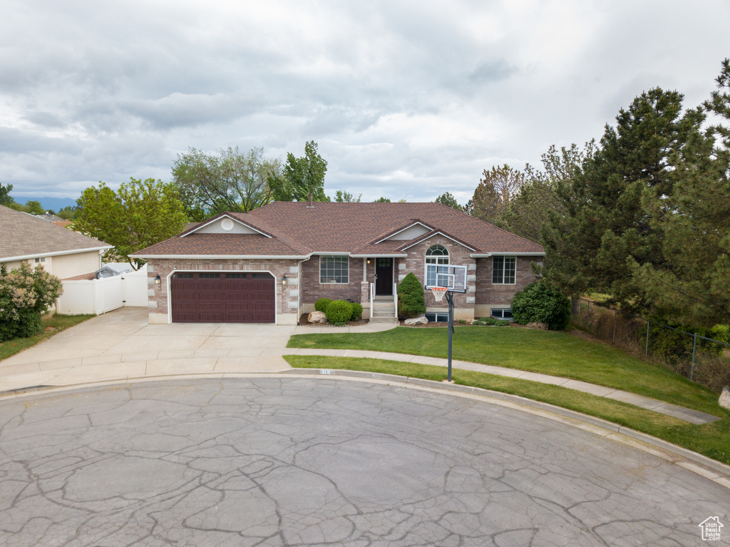Single story home featuring driveway, an attached garage, and brick siding