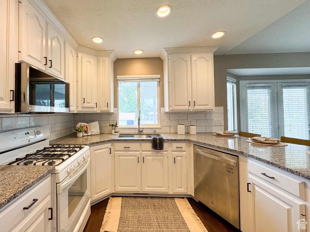Kitchen with gas range gas stove, dishwasher, a sink, wood finished floors, and white cabinets