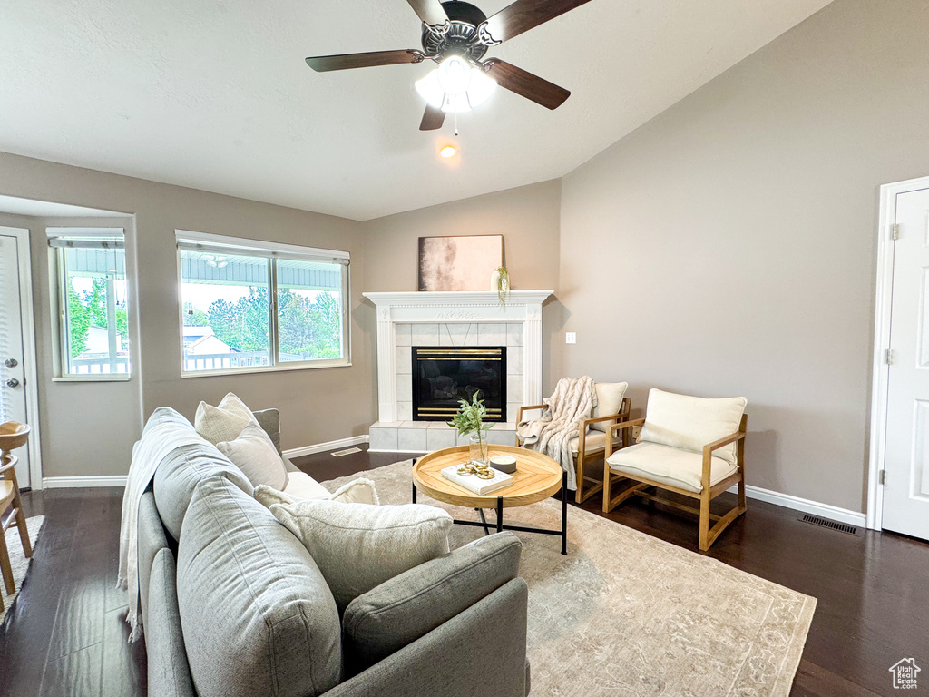 Living room featuring vaulted ceiling, baseboards, dark wood finished floors, and a tiled fireplace